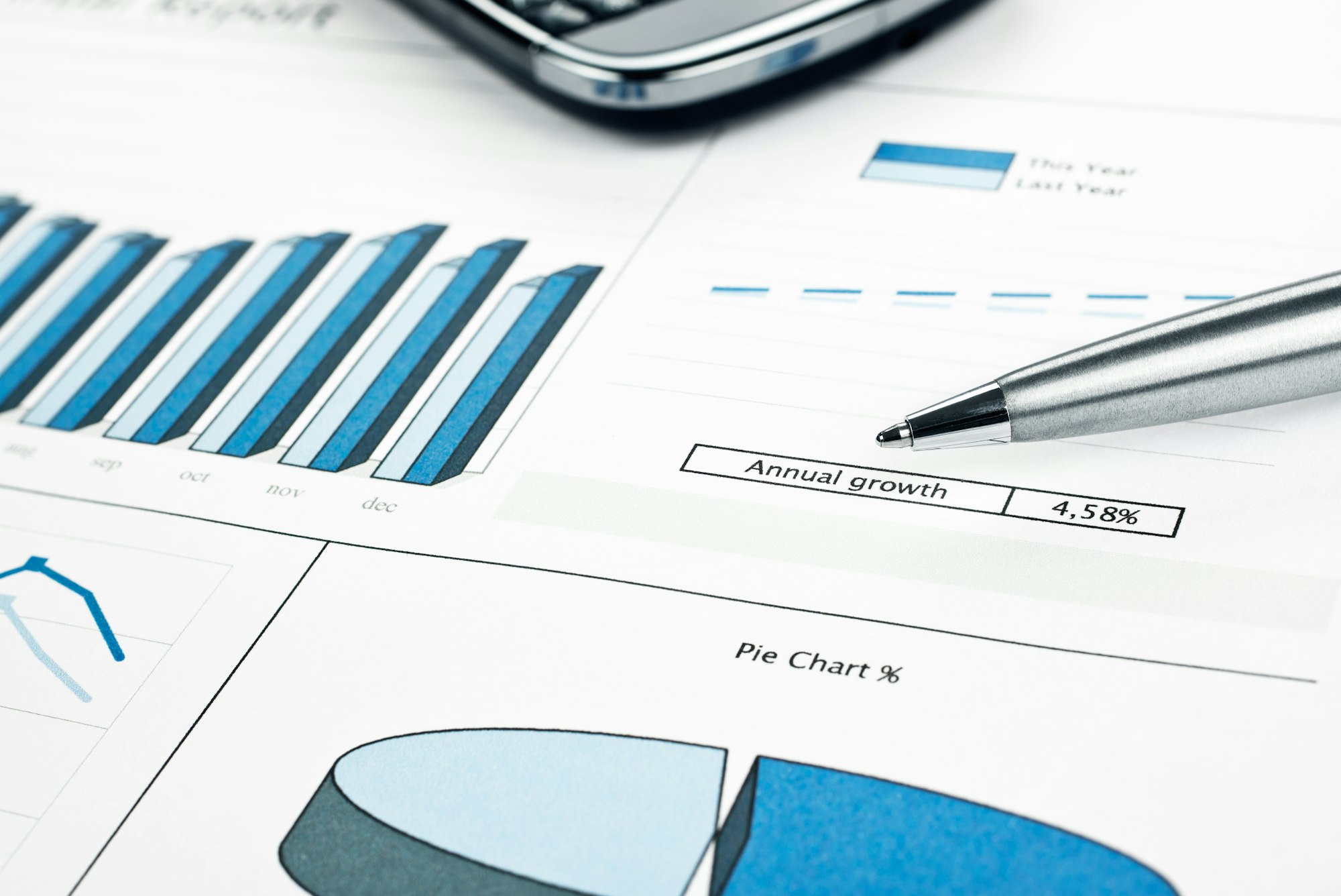 Annual growth report ink print paper, pen, smartphone. Monthly stats.