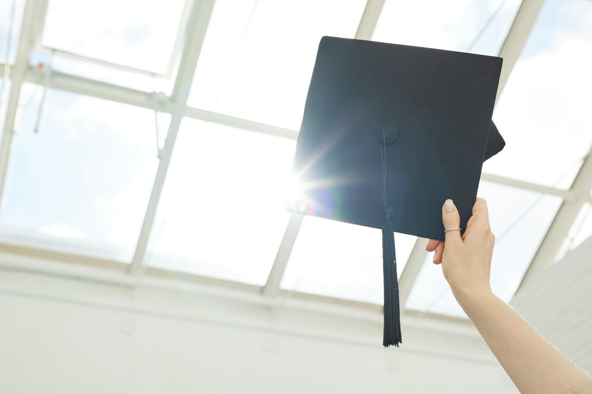 Hand holding graduation cap in sunlight