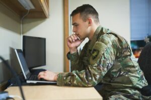 Shot of a young soldier using a laptop in the dorms of a military academy