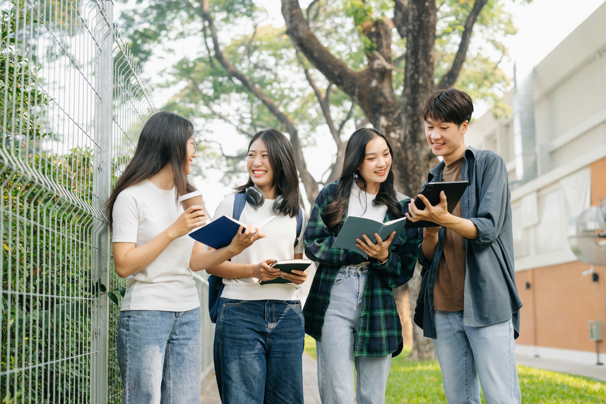 Young Asian college students and a female student group work at the campus park