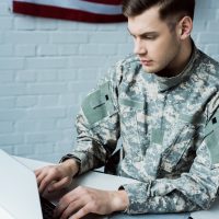 young military man using laptop in modern office